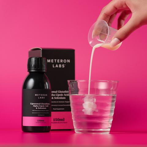 Hand pouring liquid from a small container into a glass with Meteoron Labs product in the background.